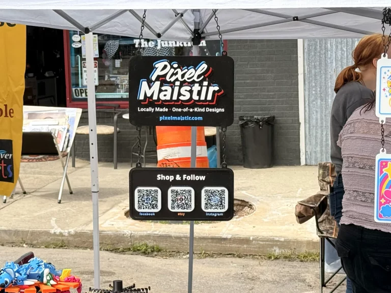 PixelMaistir booth sign with QR codes at Murphy Spring Festival 2026.